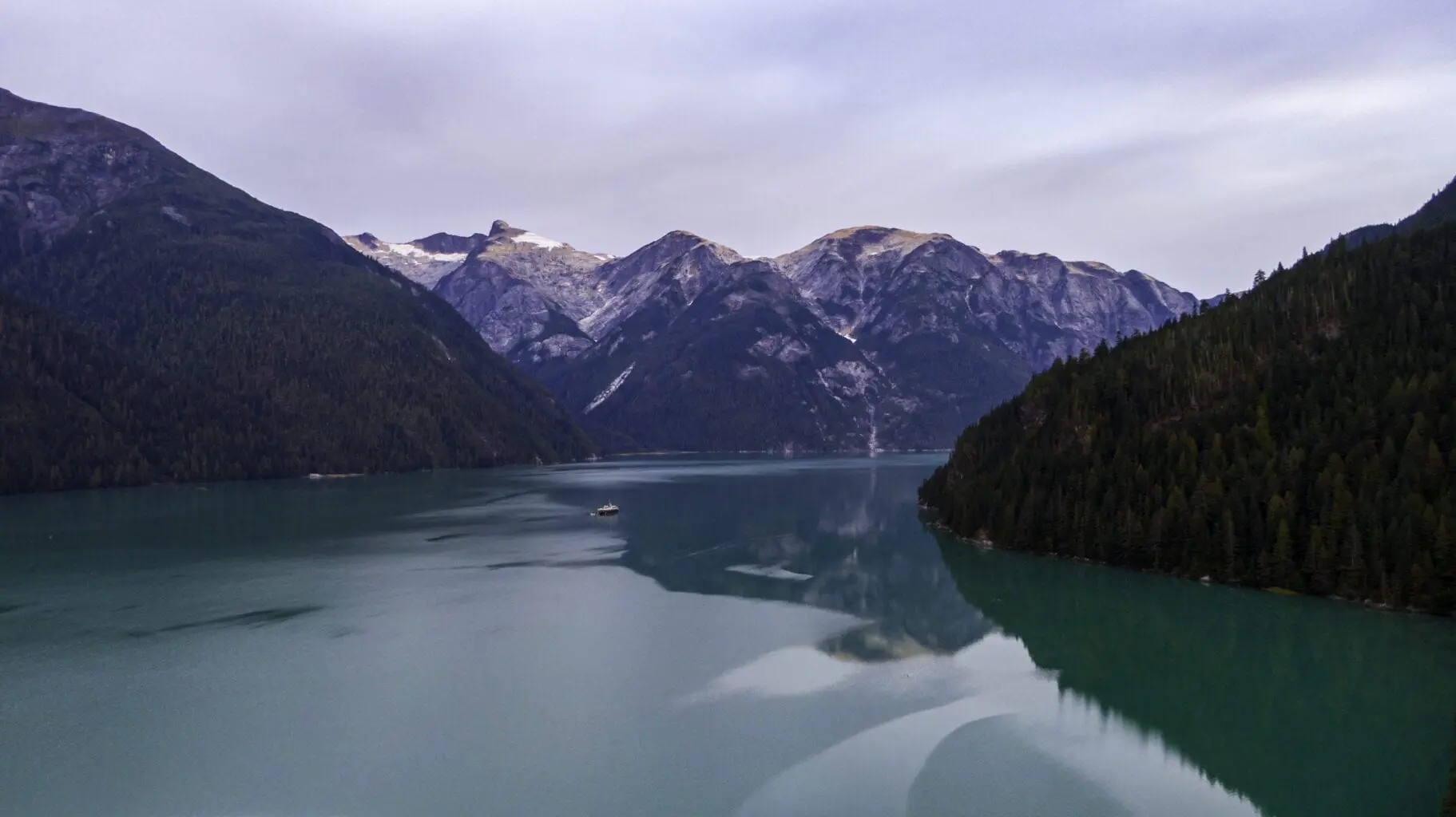 Aerial shot of catamaran on lake with vast moutains surrounding