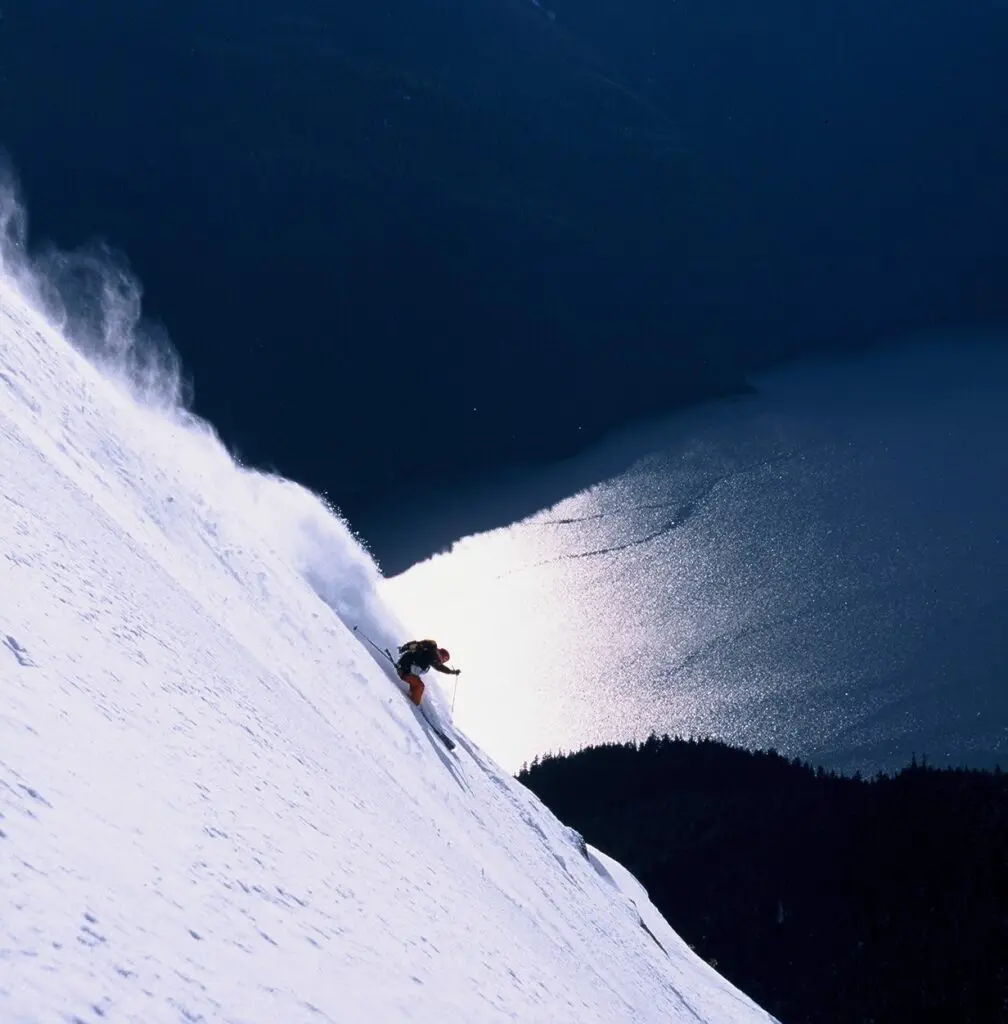 Bella Coola skiing down steep mountain face heli-skiing